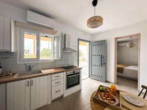 a kitchen with white cabinets and a table with a bowl of fruit at Vigla's Tiny House - Steps to the Beach in Mikri Vigla +5 photos