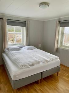 a large bed in a bedroom with two windows at Villa Nygård in Jelsa