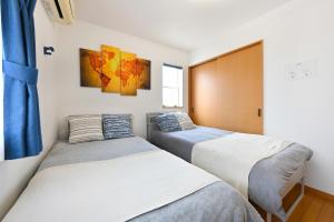 two beds in a room with blue curtains at The triangle hub Miyazaki in Miyazaki