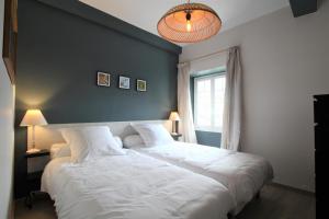a bedroom with two white beds and a blue wall at Labourdette in Lasseube