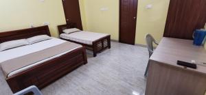 a bedroom with two beds and a desk at Carmel Stay in Madurai +2 photos