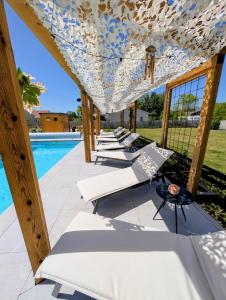 a row of lounge chairs under a pergola next to a pool at Gite Les Intemporels in Cuisery