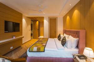 a hotel room with a bed and a flat screen tv at Tripli Hotels Royal Spring in Mussoorie