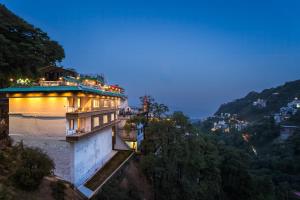 a building on the side of a hill at night at Tripli Hotels Royal Spring in Mussoorie
