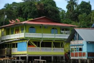 a yellow house with a red roof on the water at Bastimentos Caribean Hotel in Bocas Town