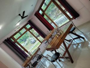 a room withwindows and a wooden table and chairs at Vikas Hotel And Restaurant in Barot  +29 photos