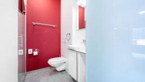 a red bathroom with a toilet and a sink at Anstatthotel Horw - app self-check-in in Lucerne +28 photos