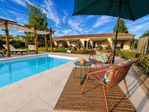 a patio with two chairs and an umbrella next to a pool at Gite Les Intemporels in Cuisery +74 photos