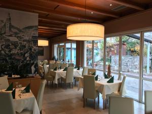 un restaurant avec des tables blanches, des chaises et des fenêtres dans l'établissement Hotel Zum Turm, à Castelrotto