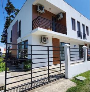 a house with balconies and a fence in front of it at Rio cottage apartment in Ureki