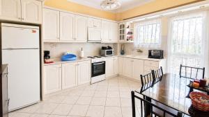 a kitchen with white cabinets and a table and a refrigerator at Vens apartment 90m2 at Eantio bay. in Aiándion