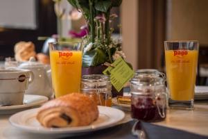 a table with a plate of bread and two glasses of orange juice at Le Bannier Hotel Restaurant in Orléans