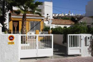 a white gate in front of a house with a palm tree at Casa Galisa in Torrevieja