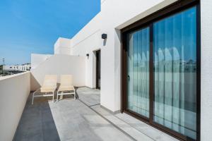 a balcony with glass doors and chairs on a building at Bungalow Fausto Sunrise in Orihuela Costa