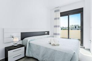 a white bedroom with two beds and a window at Bungalow Fausto Sunrise in Orihuela Costa