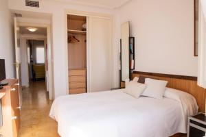 a bedroom with a white bed and a television at Aguamarina Ático Duplex Gran Terraza Cabo Roig in Orihuela