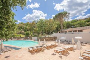 a swimming pool with lounge chairs and umbrellas at Apartment – Restanques – Swimming in Grimaud