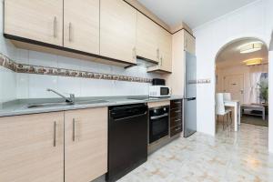 a kitchen with wooden cabinets and a sink at Playa del Pinet Apartment in La Marina +12 photos