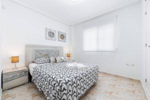a white bedroom with a bed and a window at Playa del Pinet Apartment in La Marina