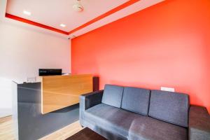 a couch in a room with an orange wall at MVTJ Hotel in Bangalore