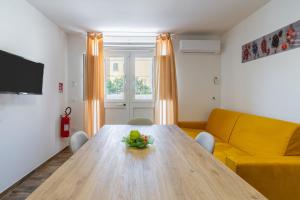 a living room with a wooden table and a yellow couch at B&B della stazione in Pachino