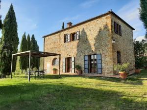 an old stone house with a table and an umbrella at Capanne di Sopra in Torrita di Siena