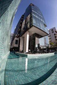 a building with a swimming pool in front of a building at Acqua Suítes Maceió in Maceió