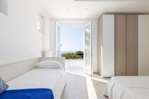 a bedroom with two beds and a large window at Villa Annalisa by PosarelliVillas in Pizzolungo +59 photos