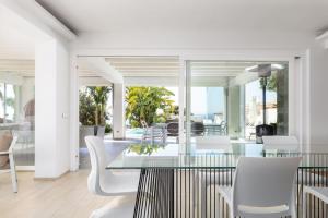 a dining room with a glass table and white chairs at Villa Annalisa by PosarelliVillas in Pizzolungo