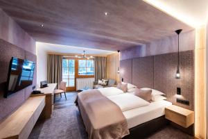 a hotel room with a large bed and a television at Hotel Sonnalp 4 Sterne Superior in Obereggen