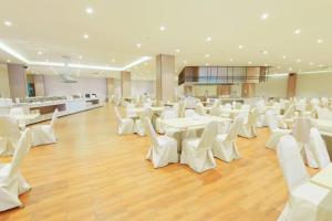 a banquet hall with white tables and white chairs at Le Srivaree Suvarnabhumi Airport Hotel in Samutprakarn