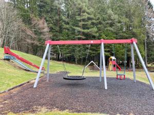 a playground with two swings and a tire at Villa Nygård in Jelsa