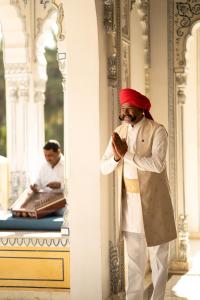 a man standing next to a pillar looking at his watch at The Leela Palace Jaipur in Jaipur