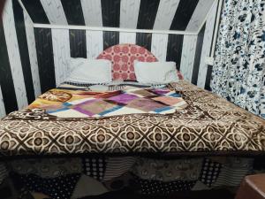 a bed with a comforter on top of it at BAKSHI lodge in Pahalgām