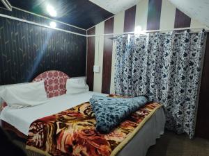 a bedroom with a bed and a curtain at BAKSHI lodge in Pahalgām