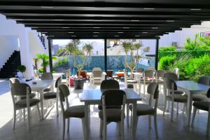 a restaurant with white tables and chairs and windows at Belmond Hotel in Ksamil