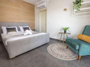 a bedroom with a large bed and a blue chair at כינור דוד המלך במנות in Manot