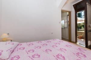 a bedroom with a pink bedspread with pink roses on it at House on the sea in Preko