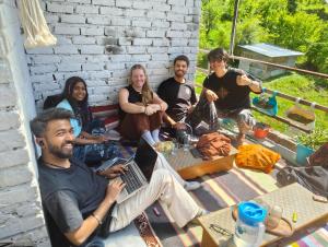 a group of people sitting around a table with a laptop at Kasolview Homestay and Peace Inn Cafe in Kasol