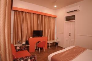 a hotel room with a bed and a desk with a television at Artistik Abode by Stay Banaras in Varanasi