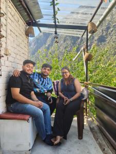 a group of three people sitting on a bench at Kasolview Homestay and Peace Inn Cafe in Kasol