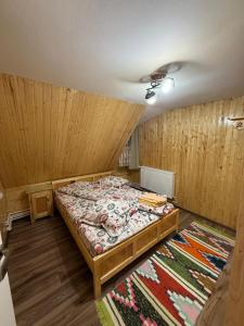 a bedroom with a bed in a room with wooden walls at Cabana Daria in Gârda de Sus