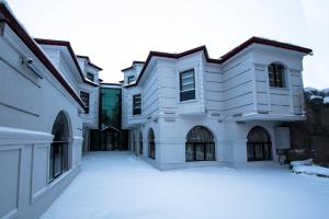 a white house with snow in the yard at Kars-i Si̇ri̇n Otel in Kars