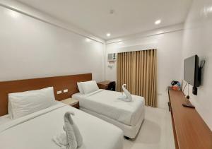 a hotel room with two beds and a flat screen tv at Cris Inn Samal in Samal