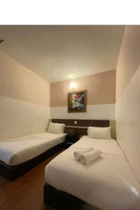 two beds in a hotel room with towels on them at Hotel O Village in Baling