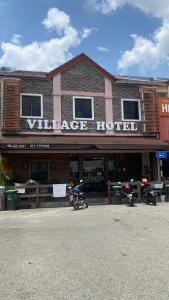 a building with motorcycles parked outside of a village hotel at Hotel O Village in Baling