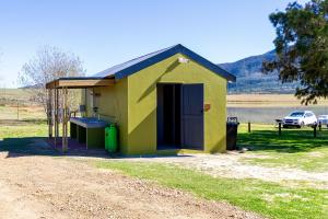 a small yellow and green shed with a car parked at Bietjiedam's Campsites in Caledon