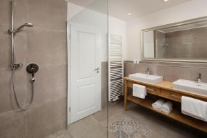 a bathroom with a shower and two sinks and a mirror at Landhaus Mucha - Ferienwohnungen - Naturpark Partner in Bolsterlang