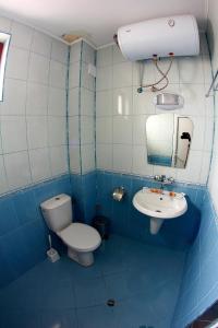 a blue tiled bathroom with a toilet and a sink at Hotel Akre in Kavarna