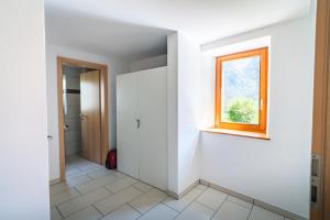 an empty hallway with a window and a door at Vallemaggia Green House in Sornico